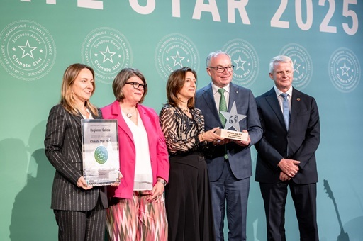 People on a stage holding certificates and an award looking into the camera